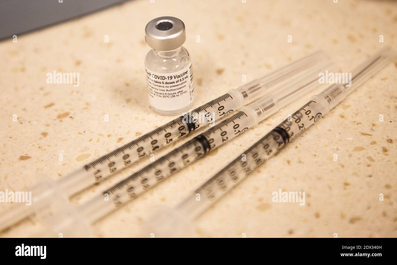 A vial of Pfizer's COVID-19 vaccine next to three syringes Stock Photo