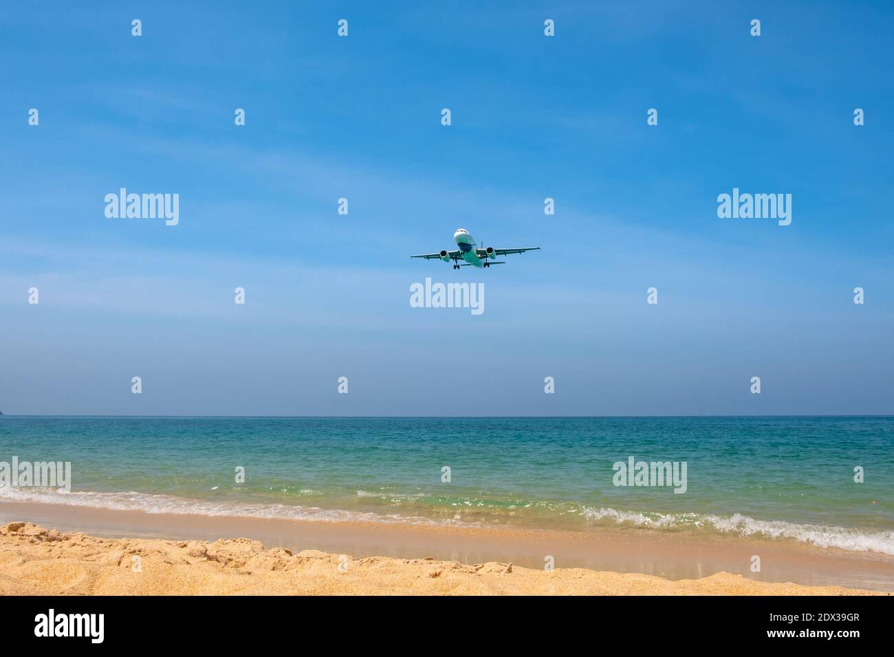 The plane comes in for landing flying over a beautiful tropical beach with fine sand and blue sea. Stock Photo