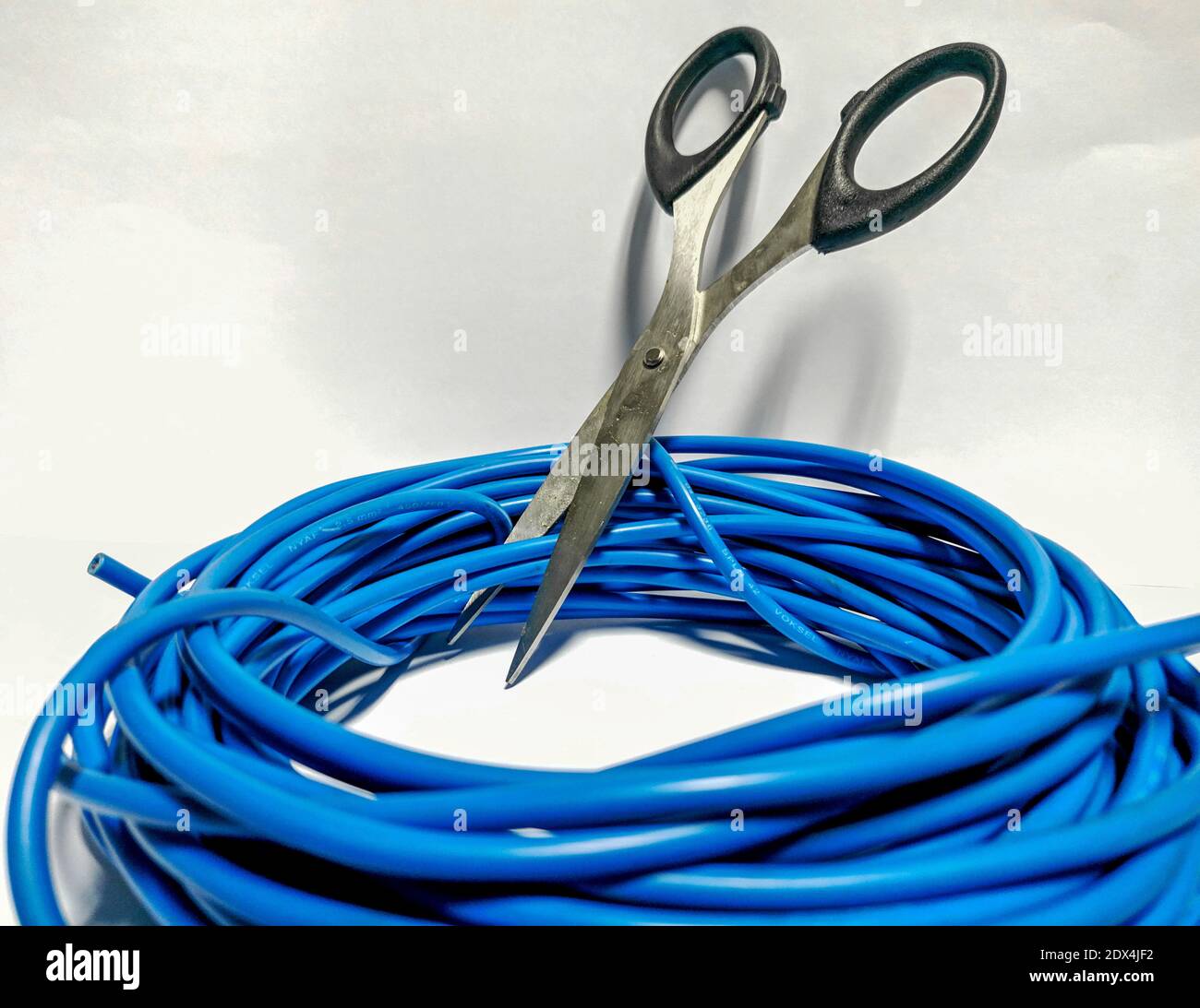 Closeup Of Scissor Cutting Wire Against White Background Stock Photo