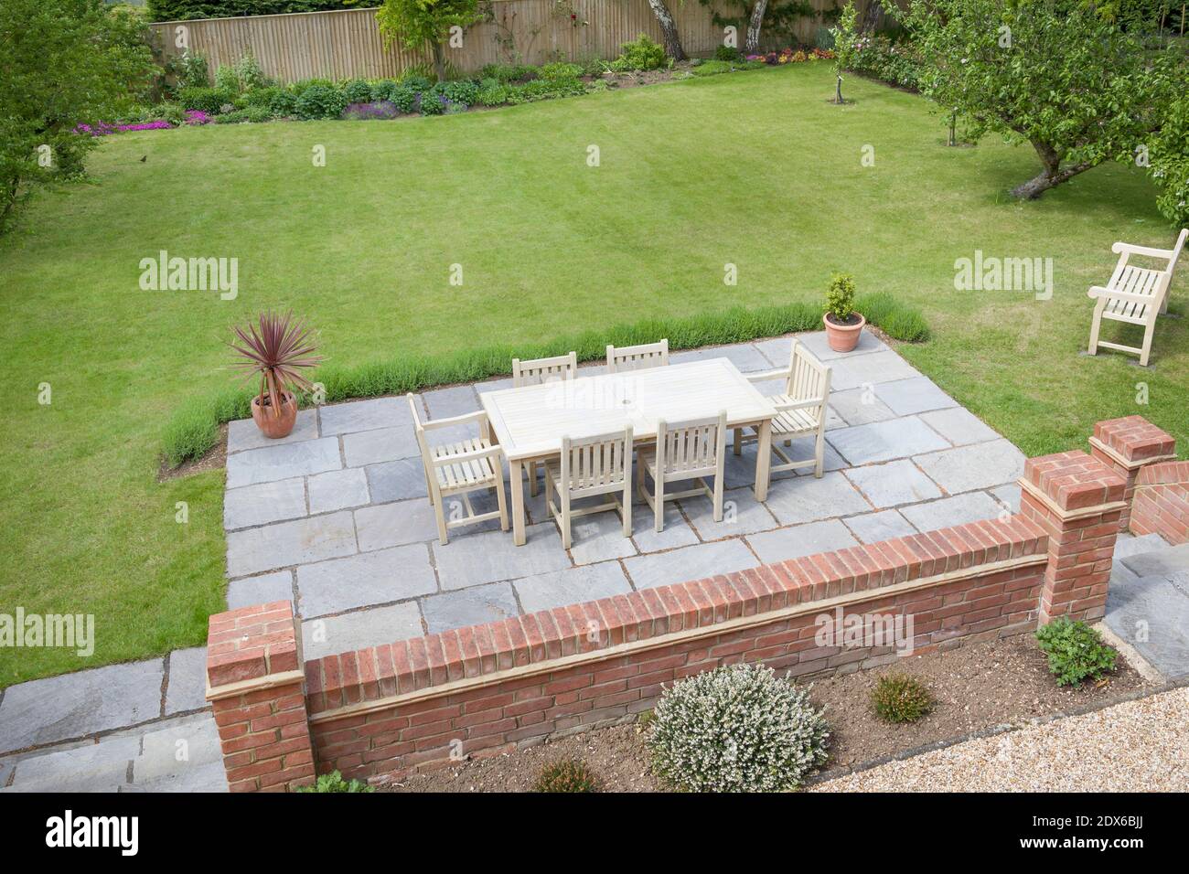 Large UK back garden with lawn and wooden patio furniture on a terrace in summer Stock Photo
