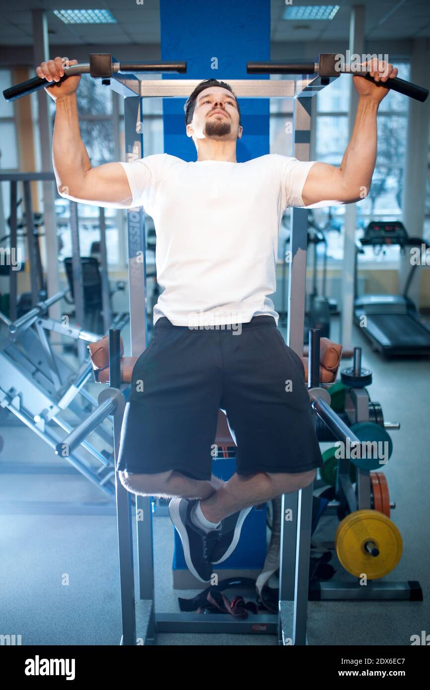 young athletic male has personal workout and pull up on bar in gym Stock Photo