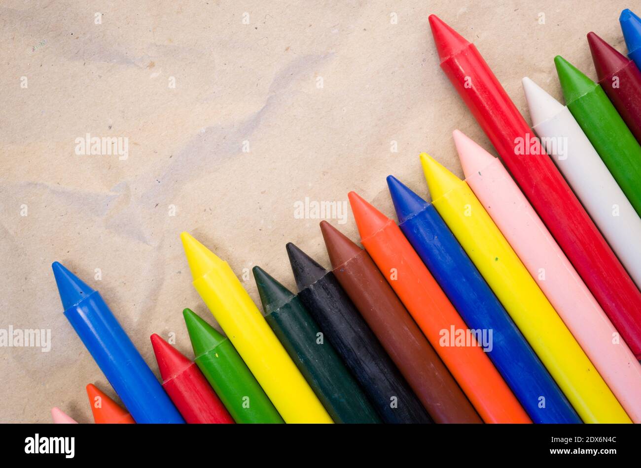 A set of lined up colored wax crayons on recycled paper background ...
