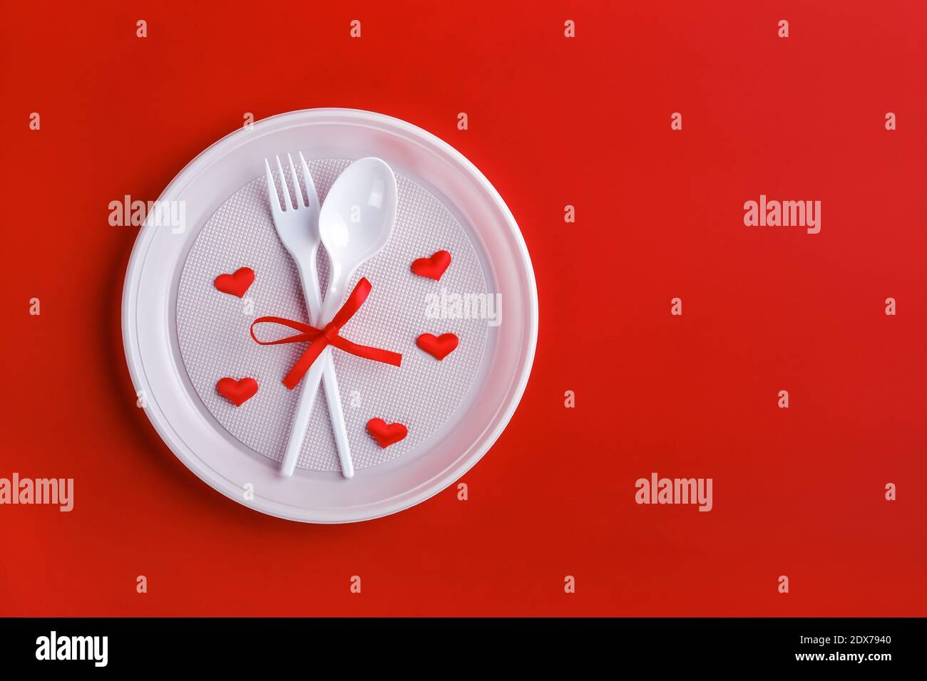 Top view of plastic white disposable fork and spoon tied with red ribbon Stock Photo
