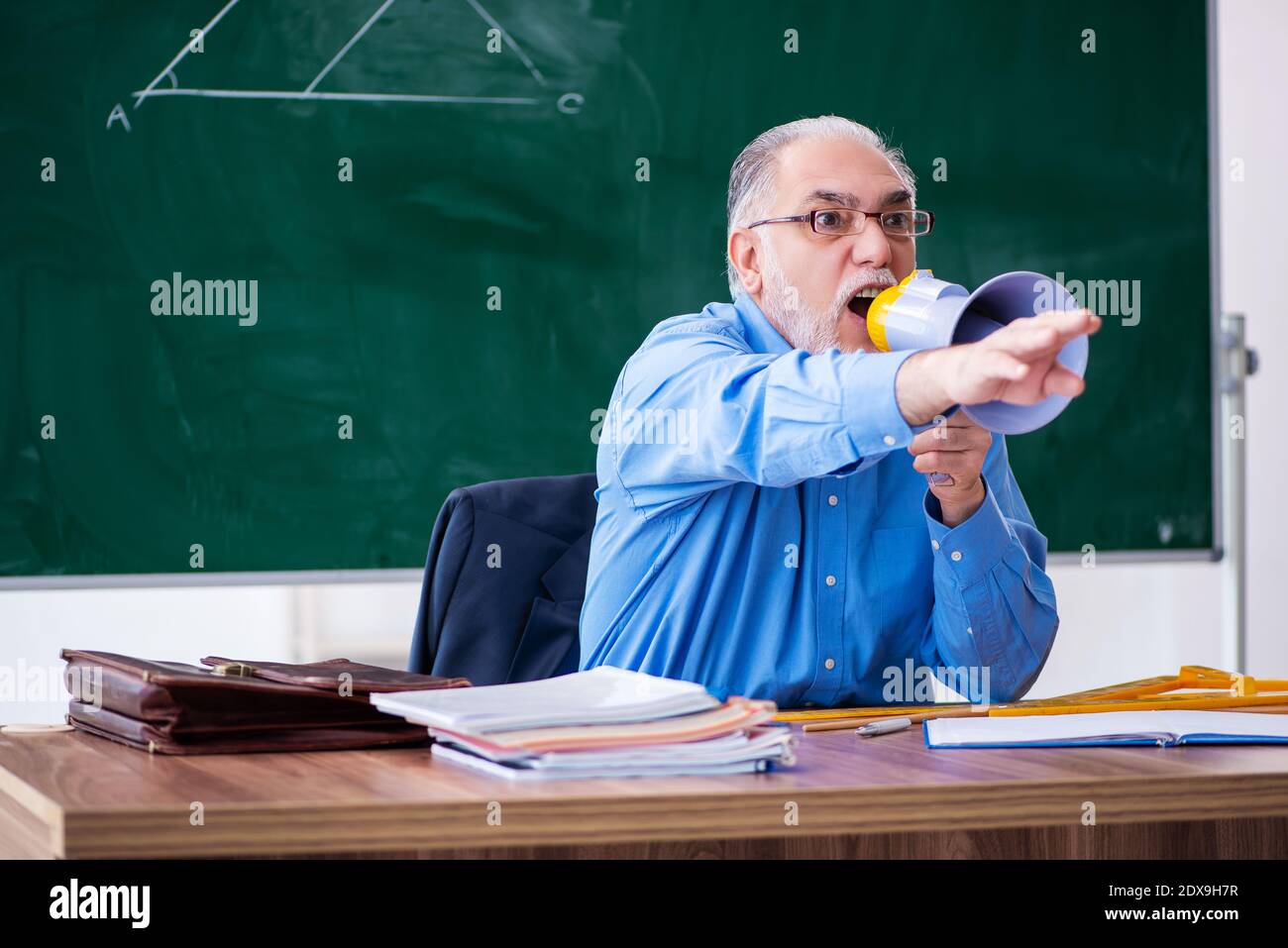 Angry male math teacher holding megaphone Stock Photo - Alamy
