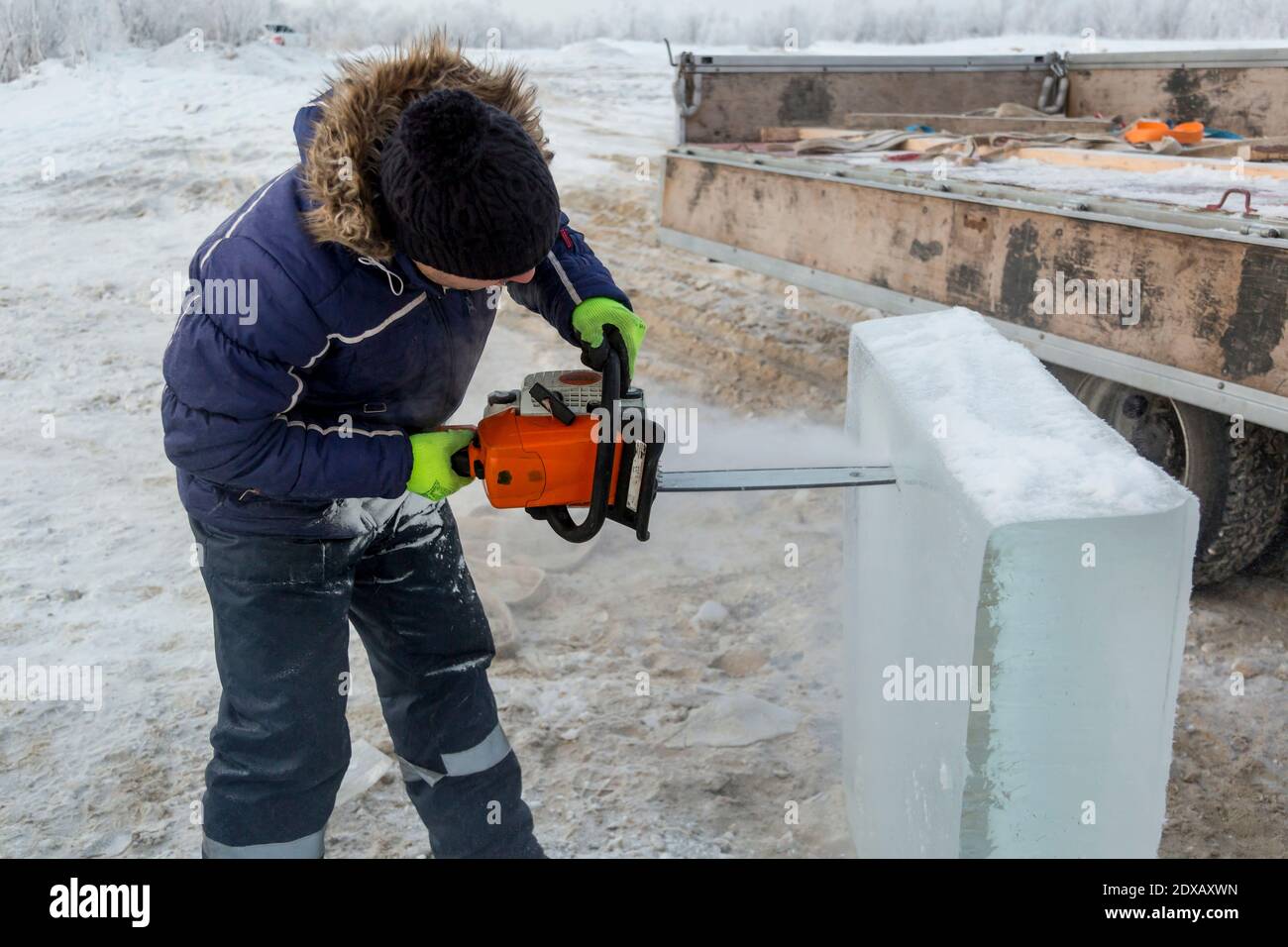 Work installer with a chainsaw in his hands undercut ice block Stock