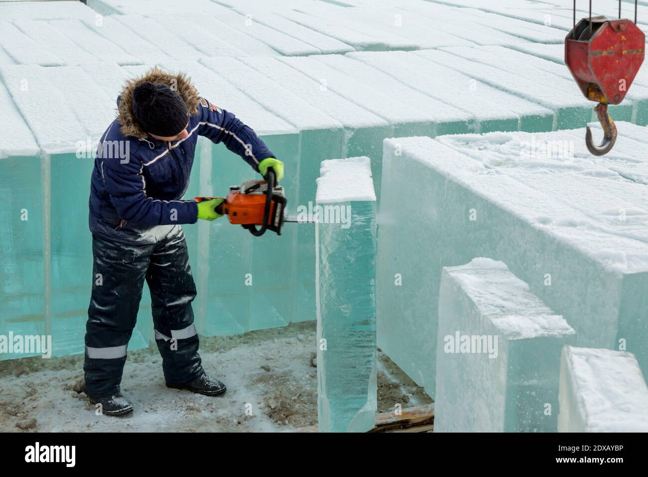 Work installer with a chainsaw in his hands undercut ice block Stock