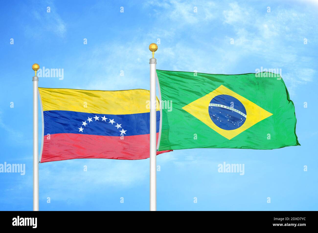 Venezuela and Brazil two flags on flagpoles and blue sky Stock Photo