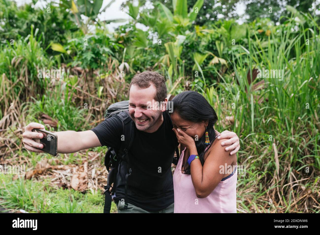Smiling male tourist taking selfie with shy woman at Misahualli, Ecuador Stock Photo