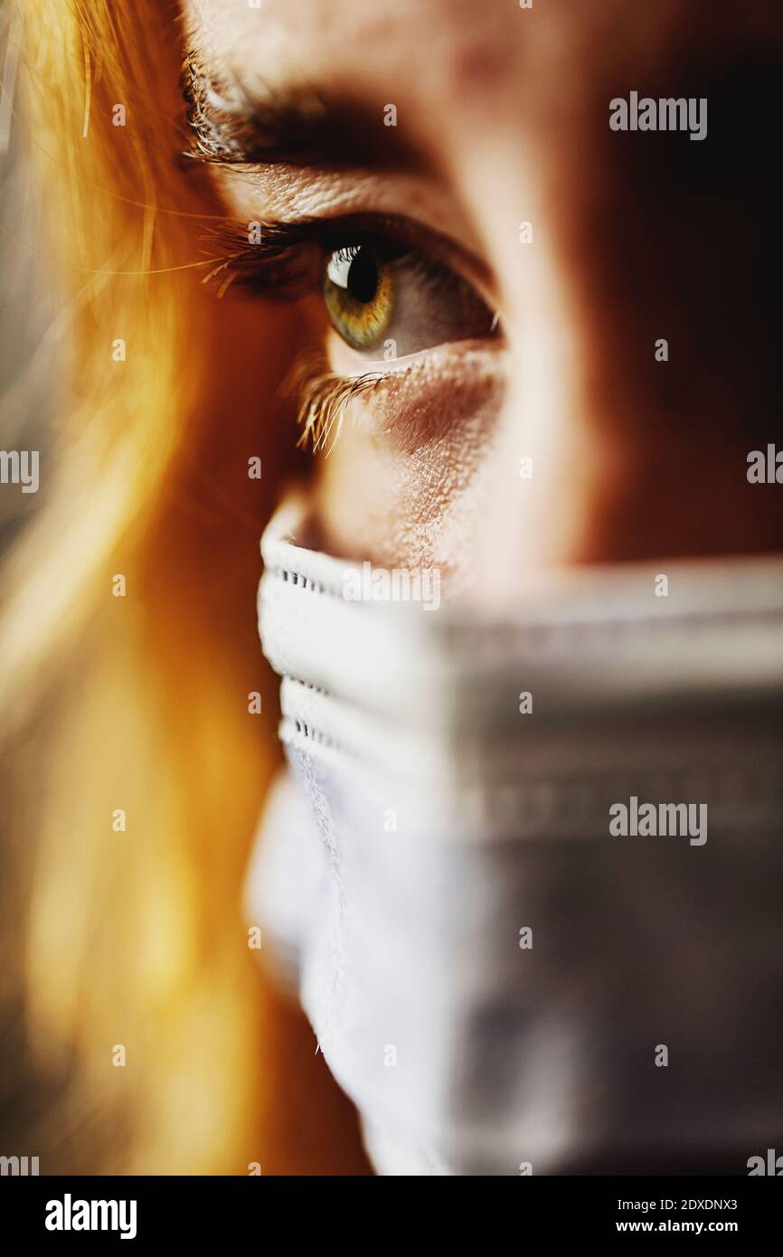 Close-up teenage girl eye wearing protective face mask on face Stock Photo