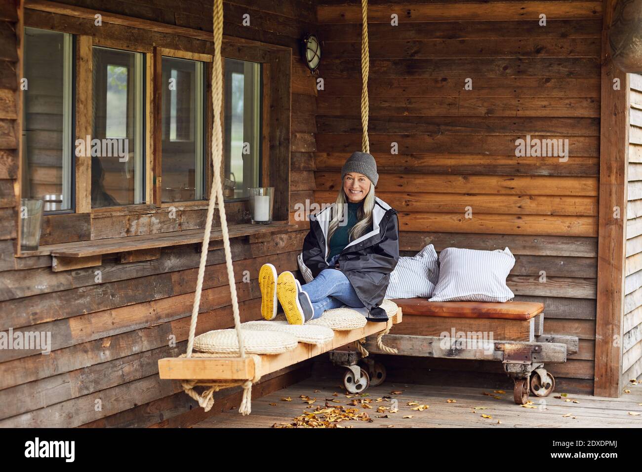 Happy mature woman relaxing on swing at patio in back yard Stock Photo ...