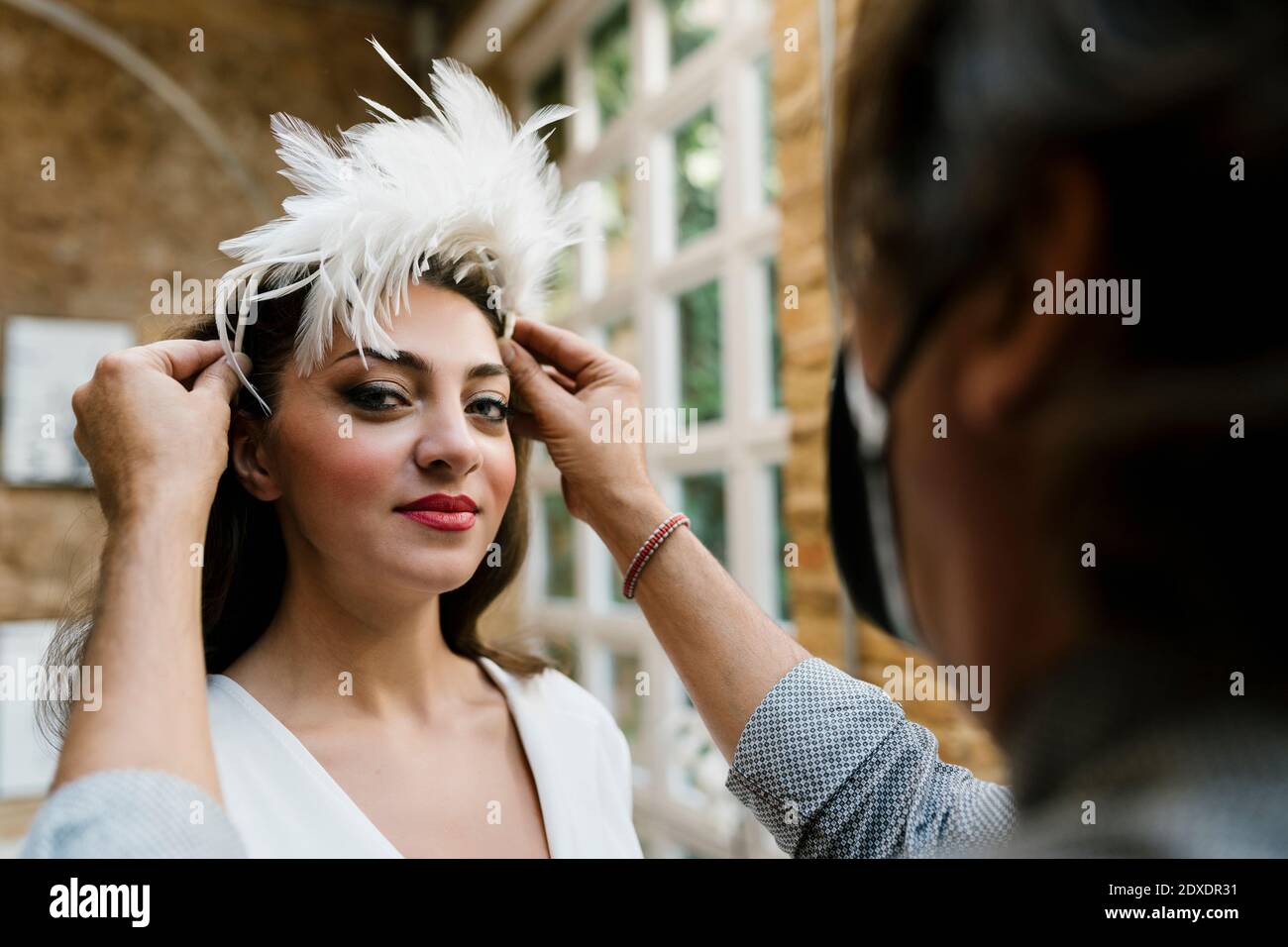 Beautiful bride having hair styled by male stylist at salon on wedding Stock Photo