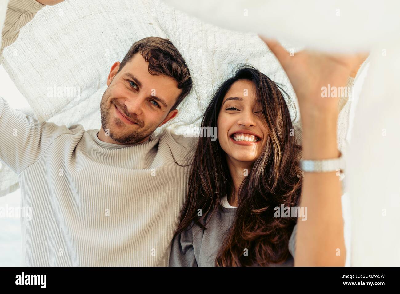 Young couple smiling while standing below shawl Stock Photo