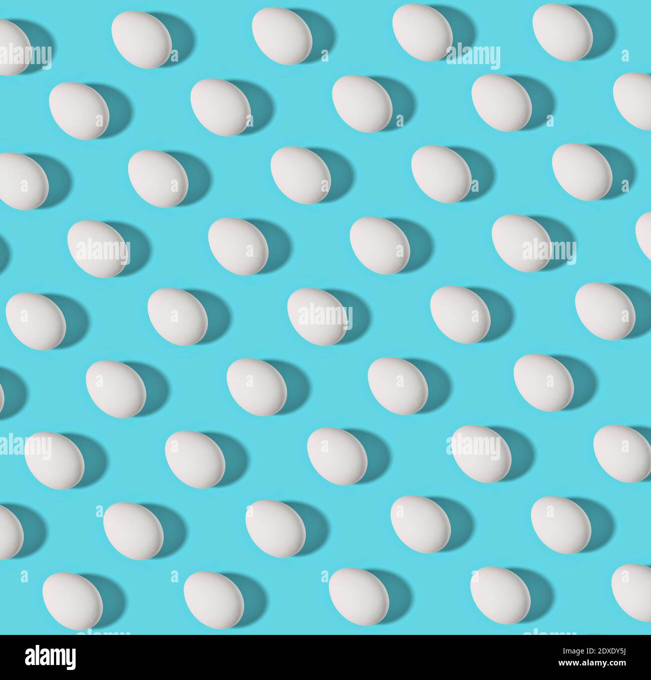 Pattern of white chicken eggs against blue background Stock Photo