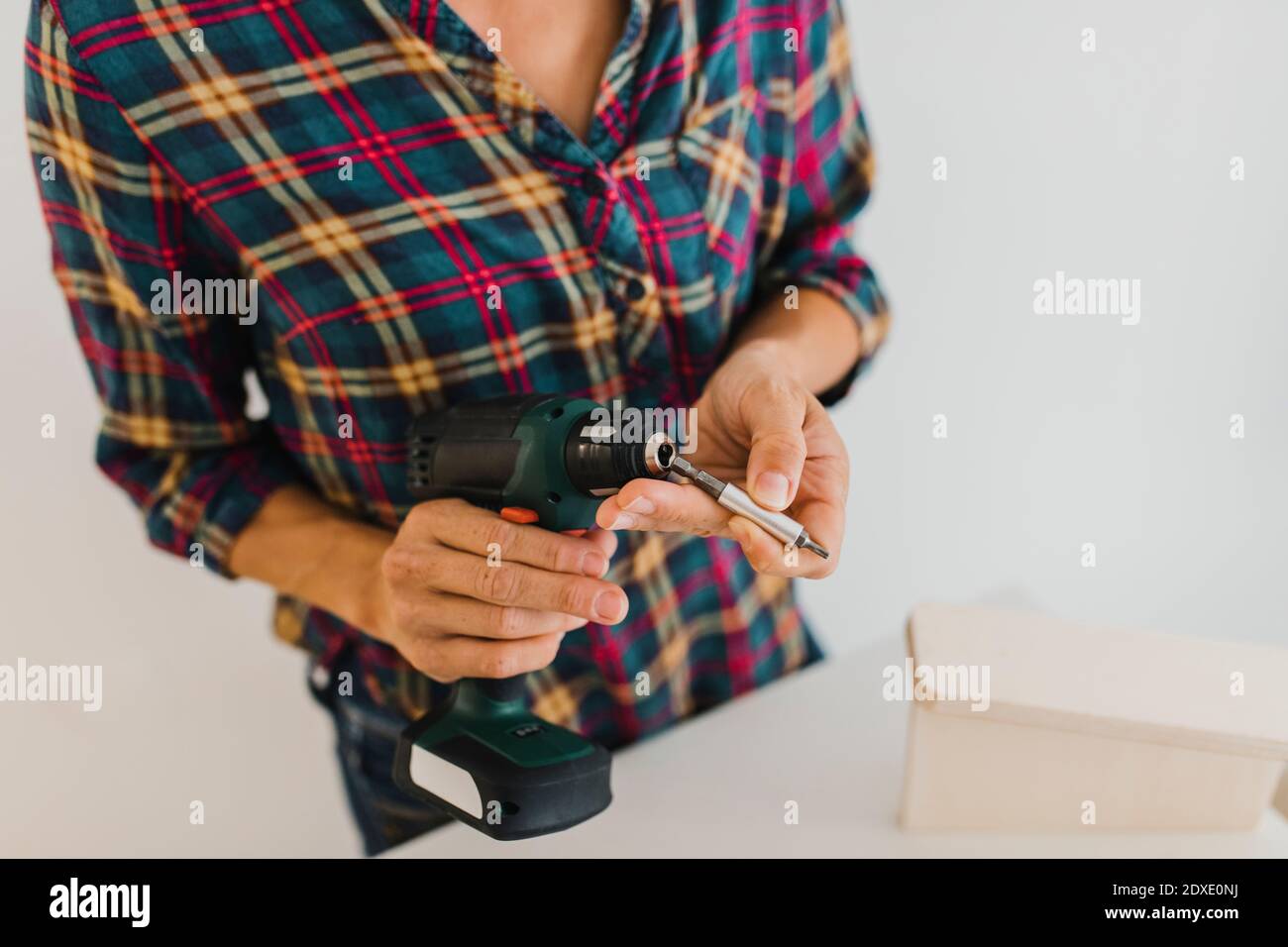 Woman putting screwdriver bit in power tool while standing at home Stock Photo