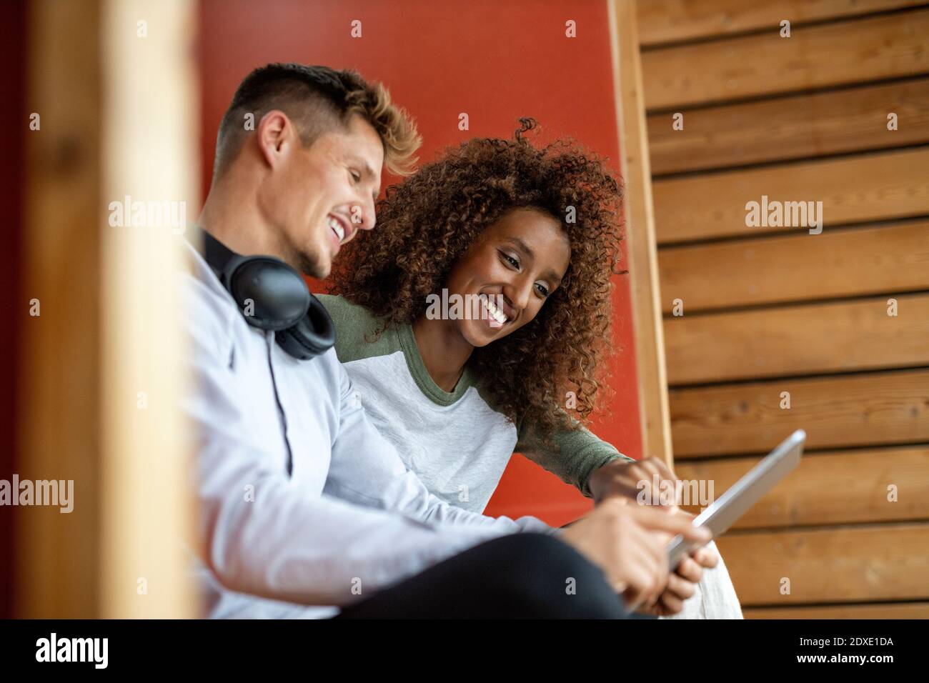 Smiling young couple using digital tablet while sitting at home Stock Photo