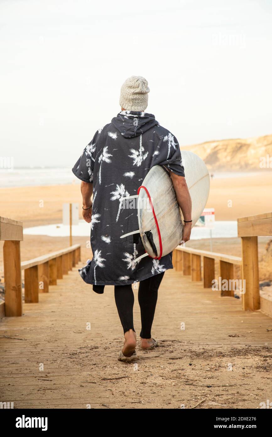 Male surfer carrying surfboard on boardwalk at beach Stock Photo Alamy