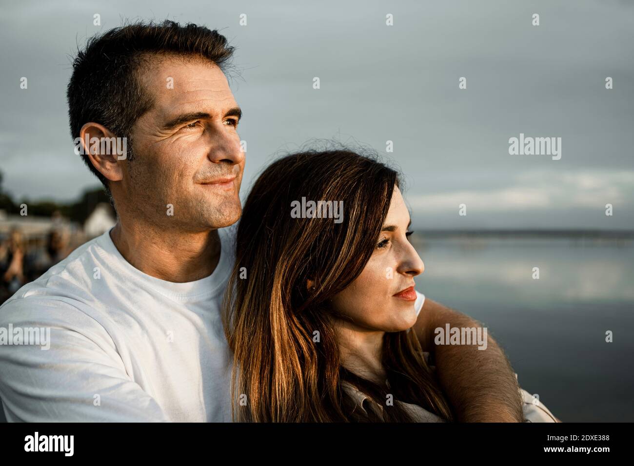 Smiling man looking away while embracing woman Stock Photo