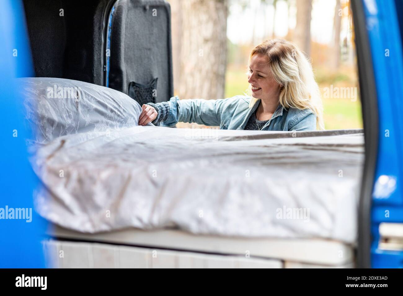 Smiling woman adjusting bed in motor home Stock Photo