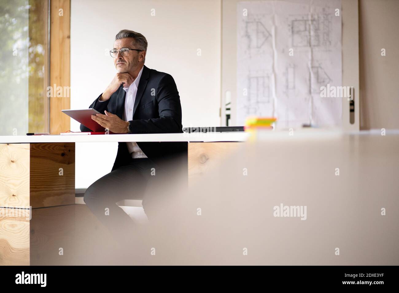 Thoughtful businessman using digital tablet while sitting at home Stock Photo