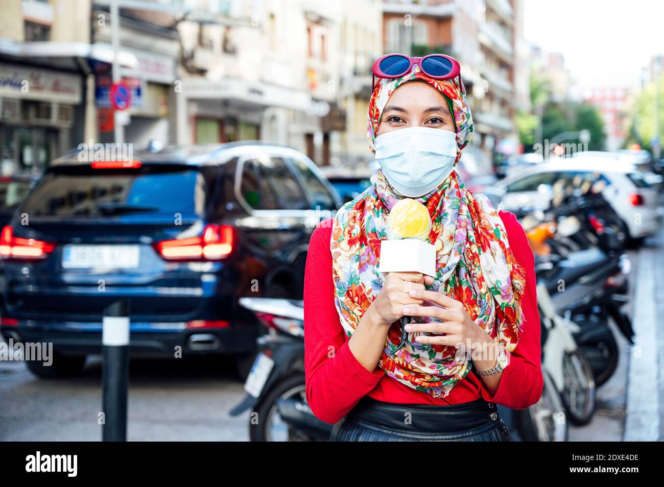 Muslim female journalist reporting in city during pandemic Stock Photo