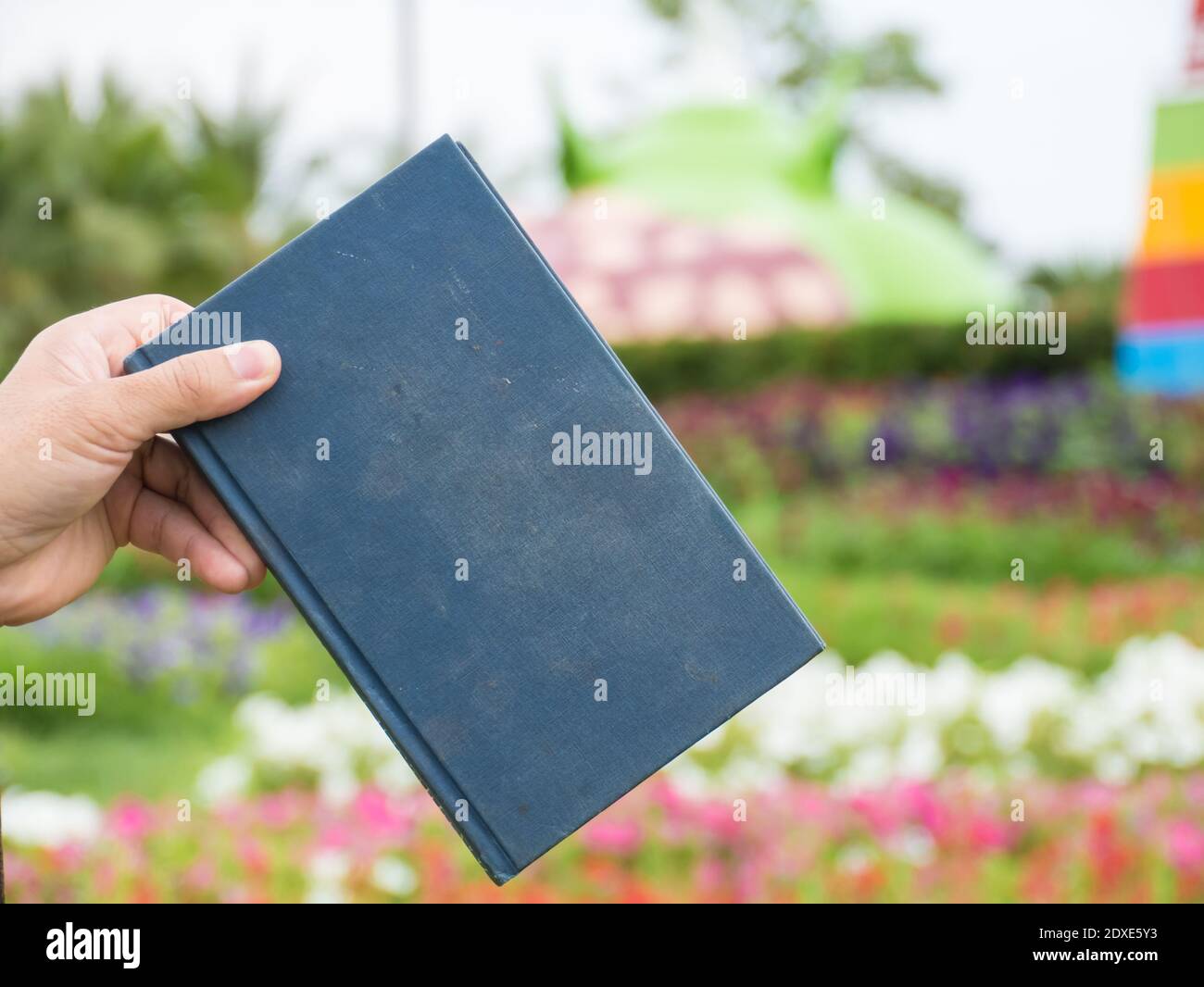 Cropped Hand Holding Diary Against Plants Stock Photo