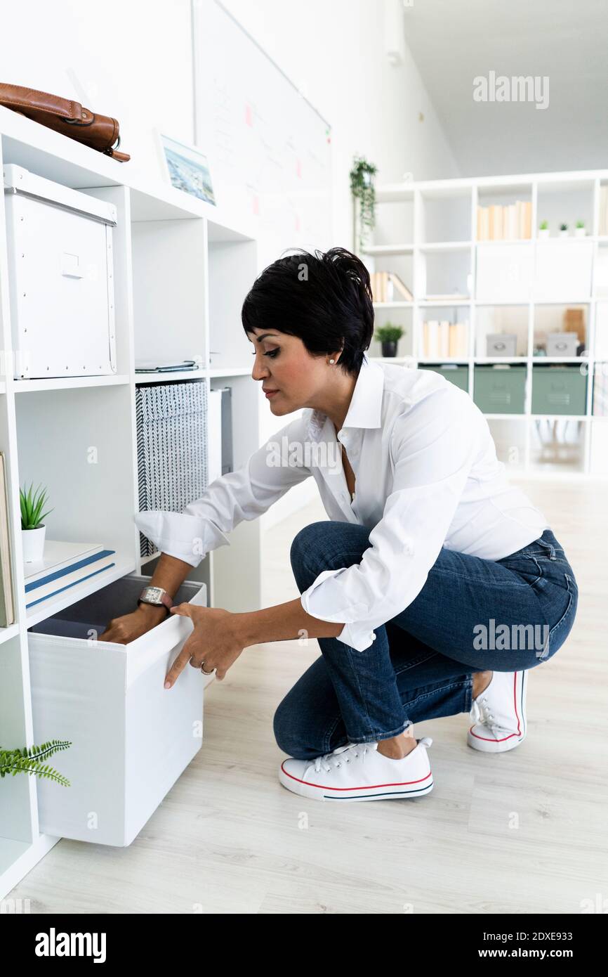 Businesswoman organizing office shelves Stock Photo