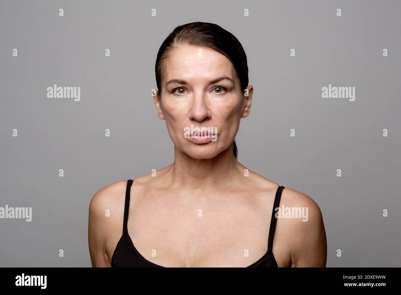 Mature woman with slicked back hair against gray background Stock Photo