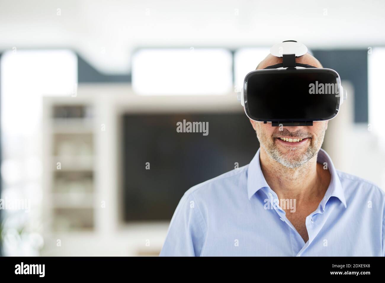 Businessman using virtual reality headset while standing at home Stock Photo