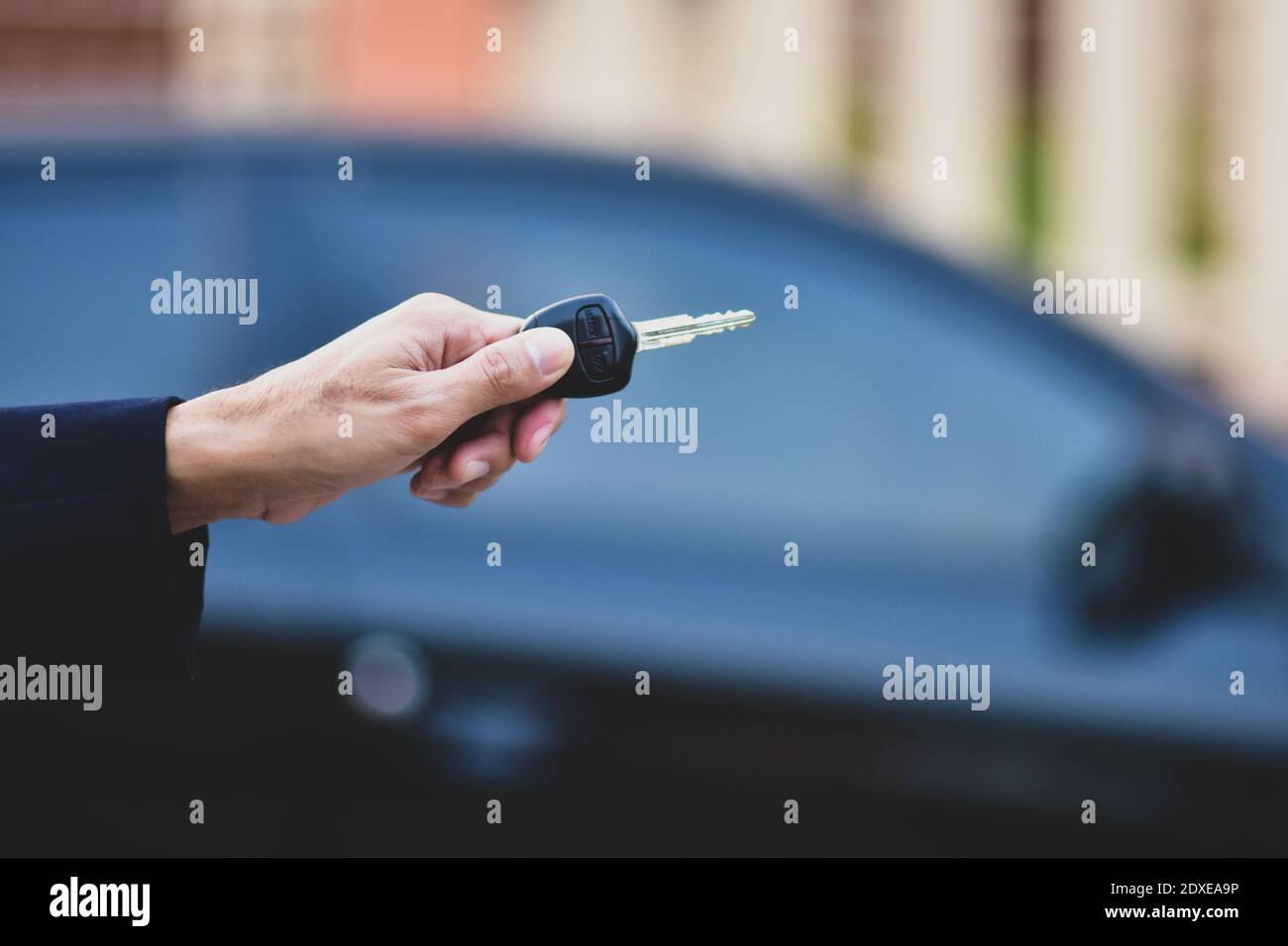 Hand holding Key and Car parked background Stock Photo - Alamy