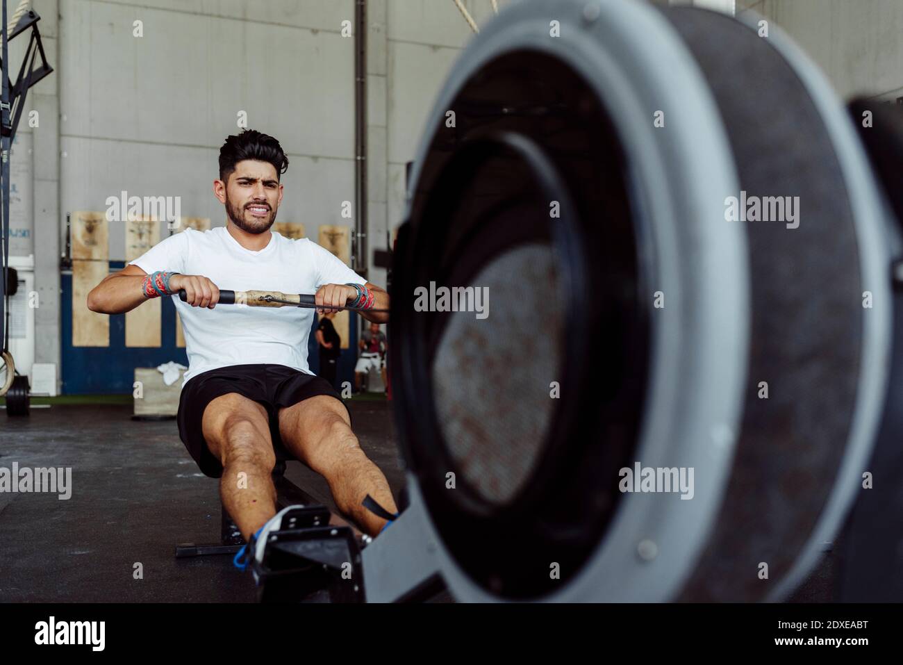 Athlete exercising with rowing machine at gym Stock Photo