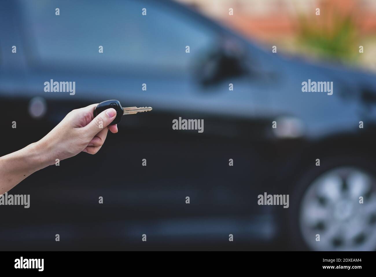Hand holding Key and Car parked background Stock Photo - Alamy