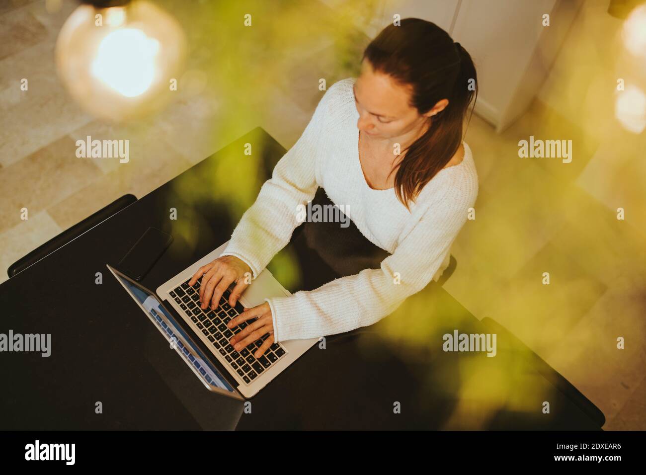 Woman using laptop at kitchen island Stock Photo