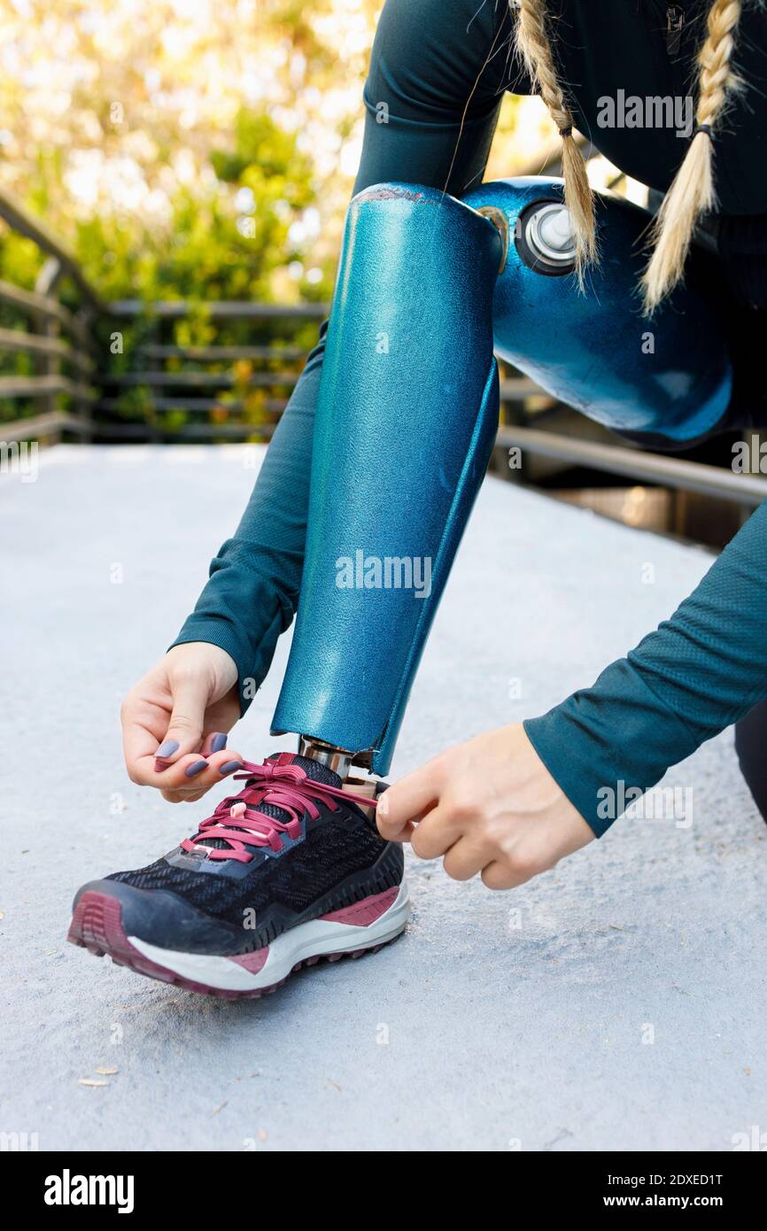 Athlete tying shoelace of prosthetic leg shoe on bridge Stock Photo