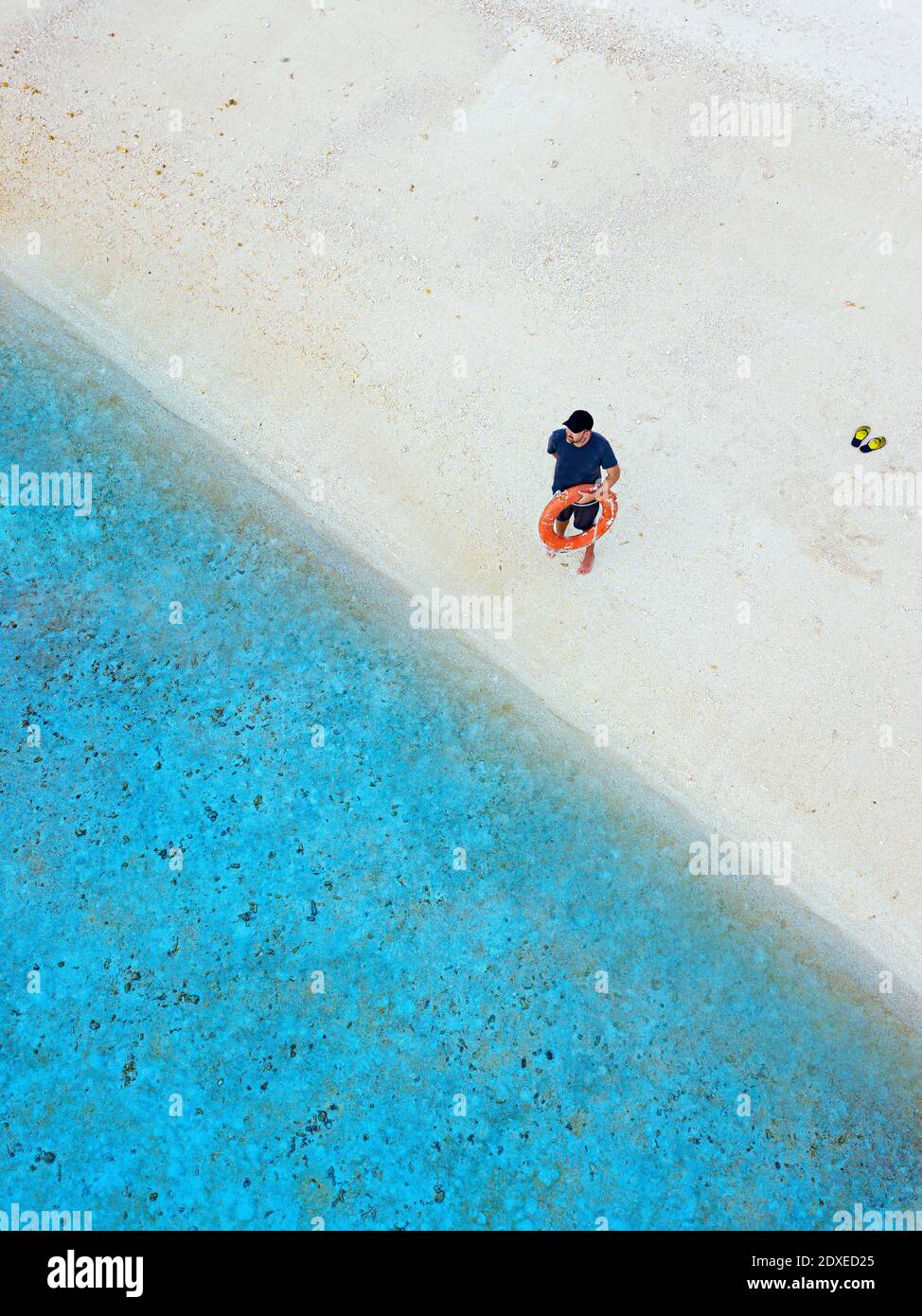 Man holding inflatable ring while standing on shore at beach Stock Photo