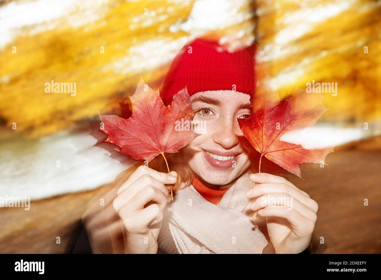 Teenage girl smiling while holding maple leaves outdoors Stock Photo