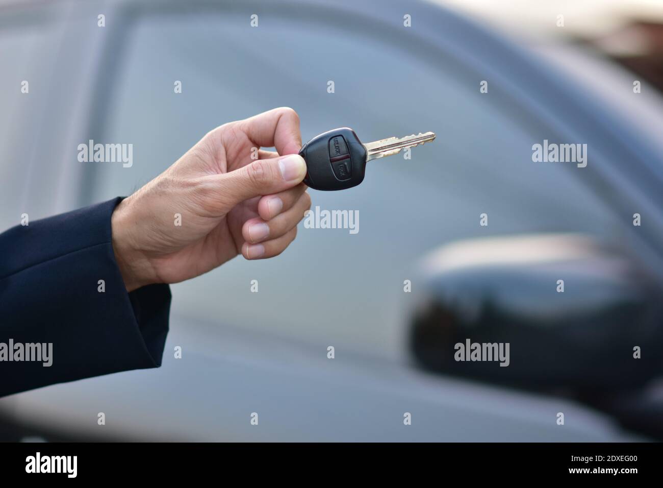 Salesman holding Key of car and car parked background Stock Photo - Alamy