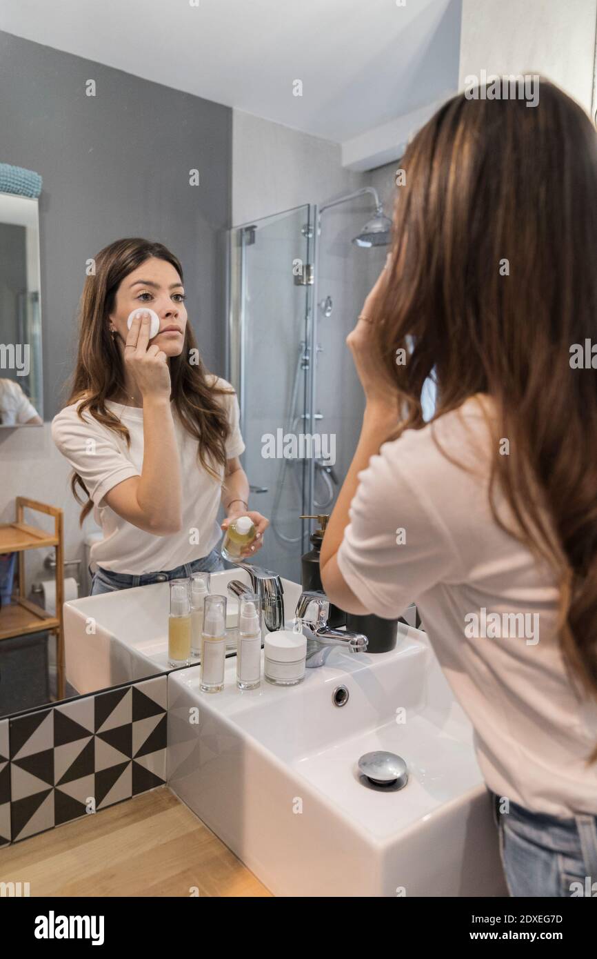 Young woman doing make-up while standing in bathroom at home Stock Photo