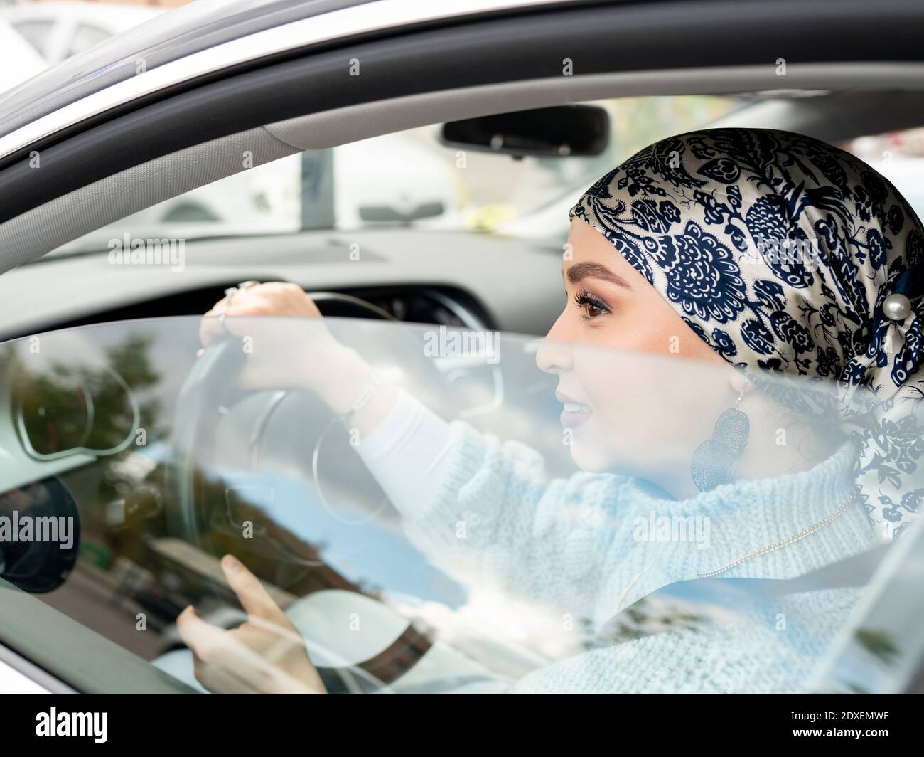 Woman wearing headscarf driving car at city Stock Photo
