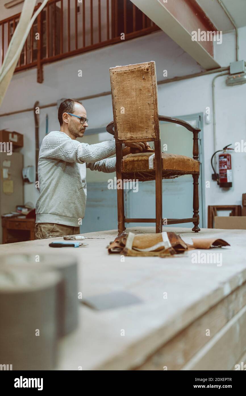 Craftsman restoring arm chair while working at workshop Stock Photo