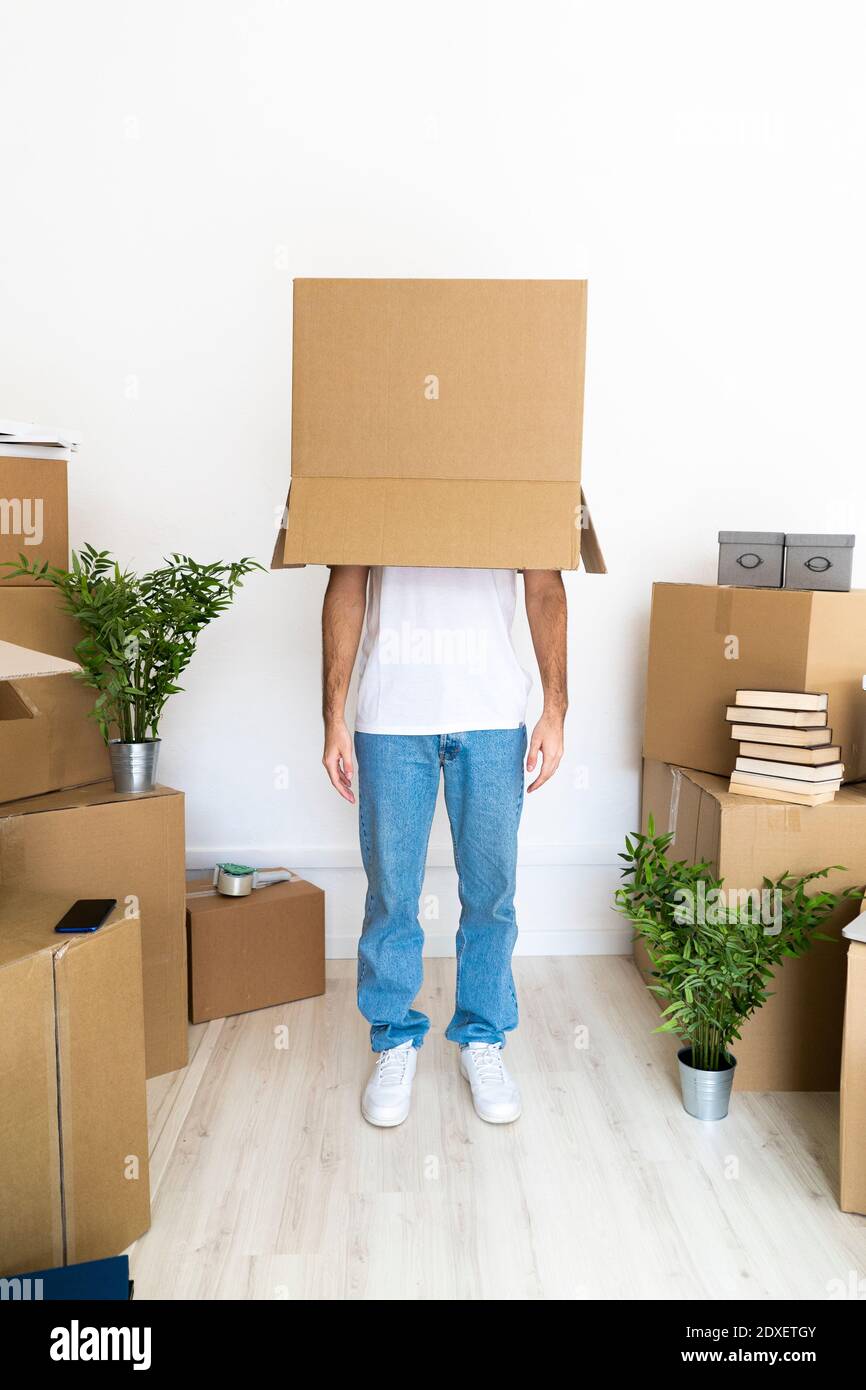 Man covering head with cardboard box while standing in new house Stock Photo