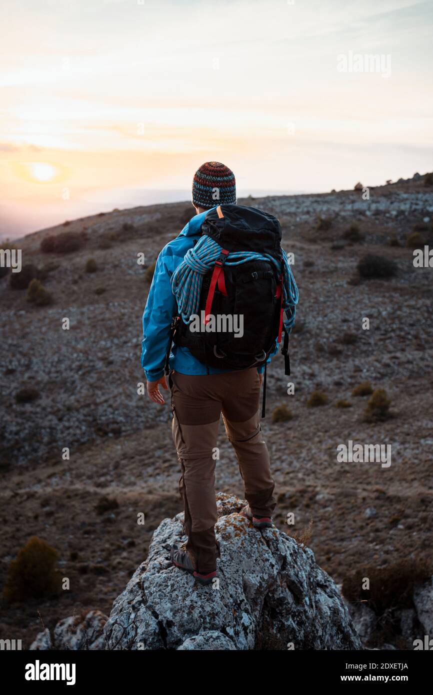 Male hiker looking at view from rock mountain during sunset Stock Photo