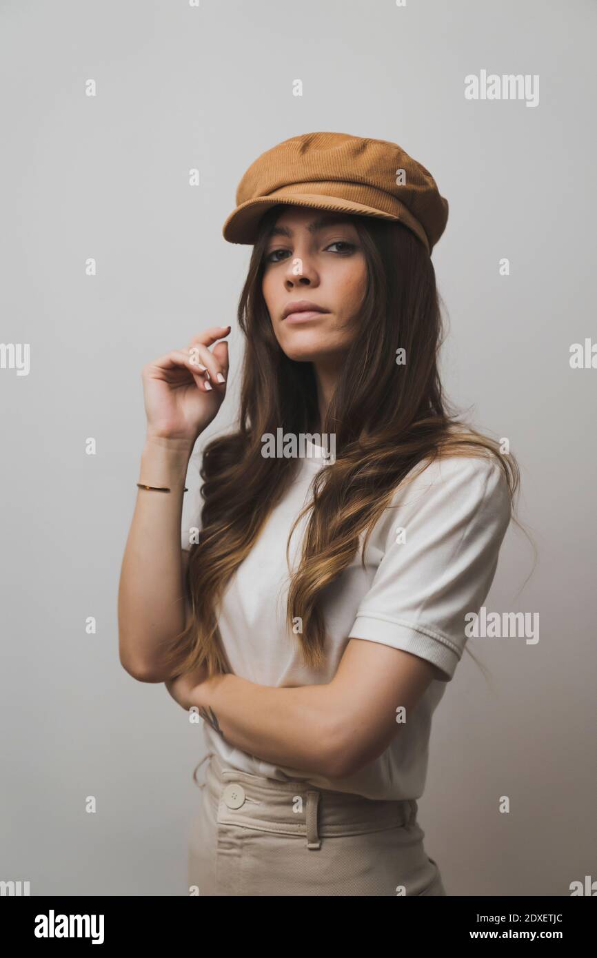 Young beautiful woman wearing cap standing against wall Stock Photo - Alamy