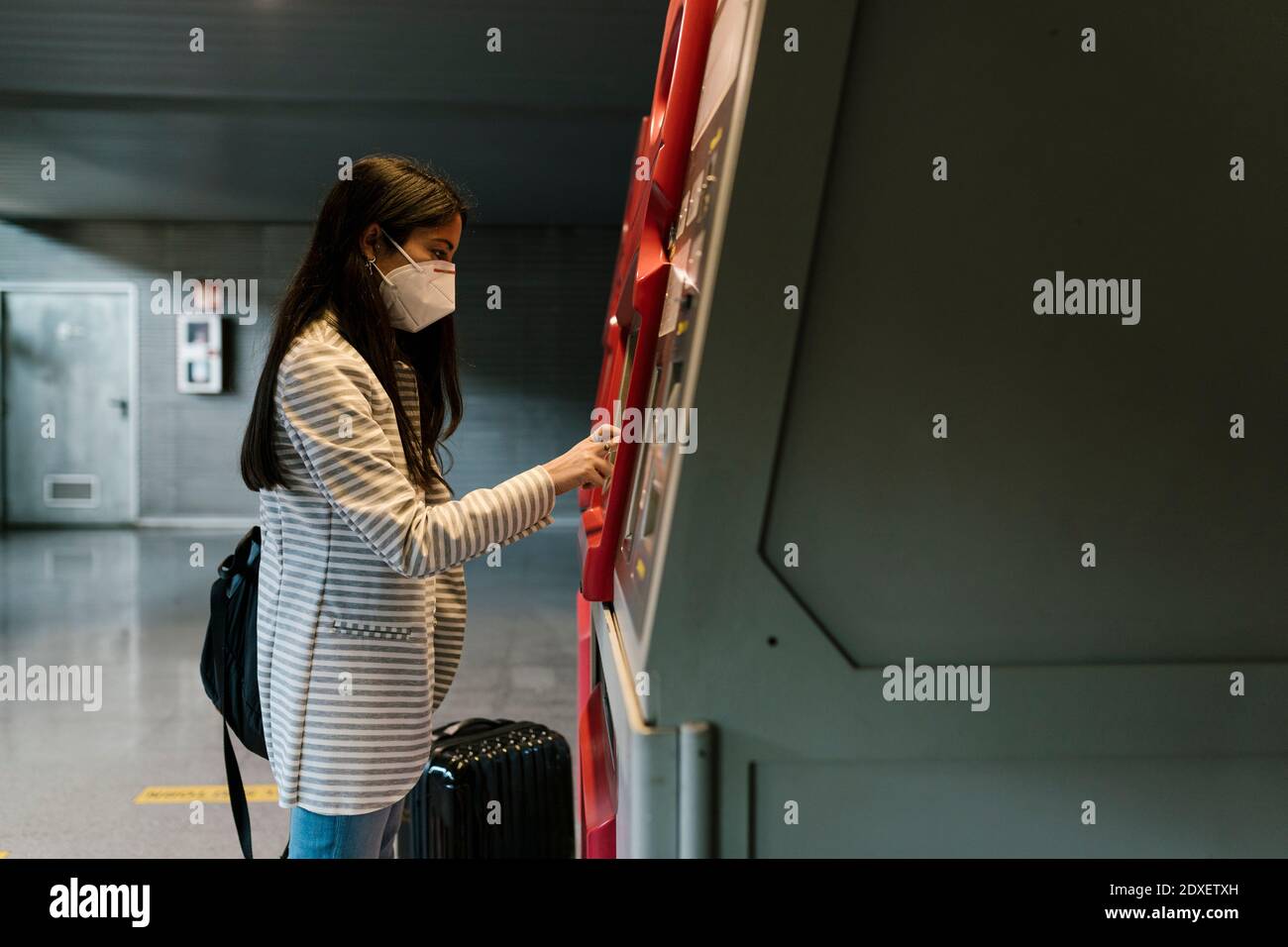 Woman with face mask using kiosk for buying train ticket during COVID ...