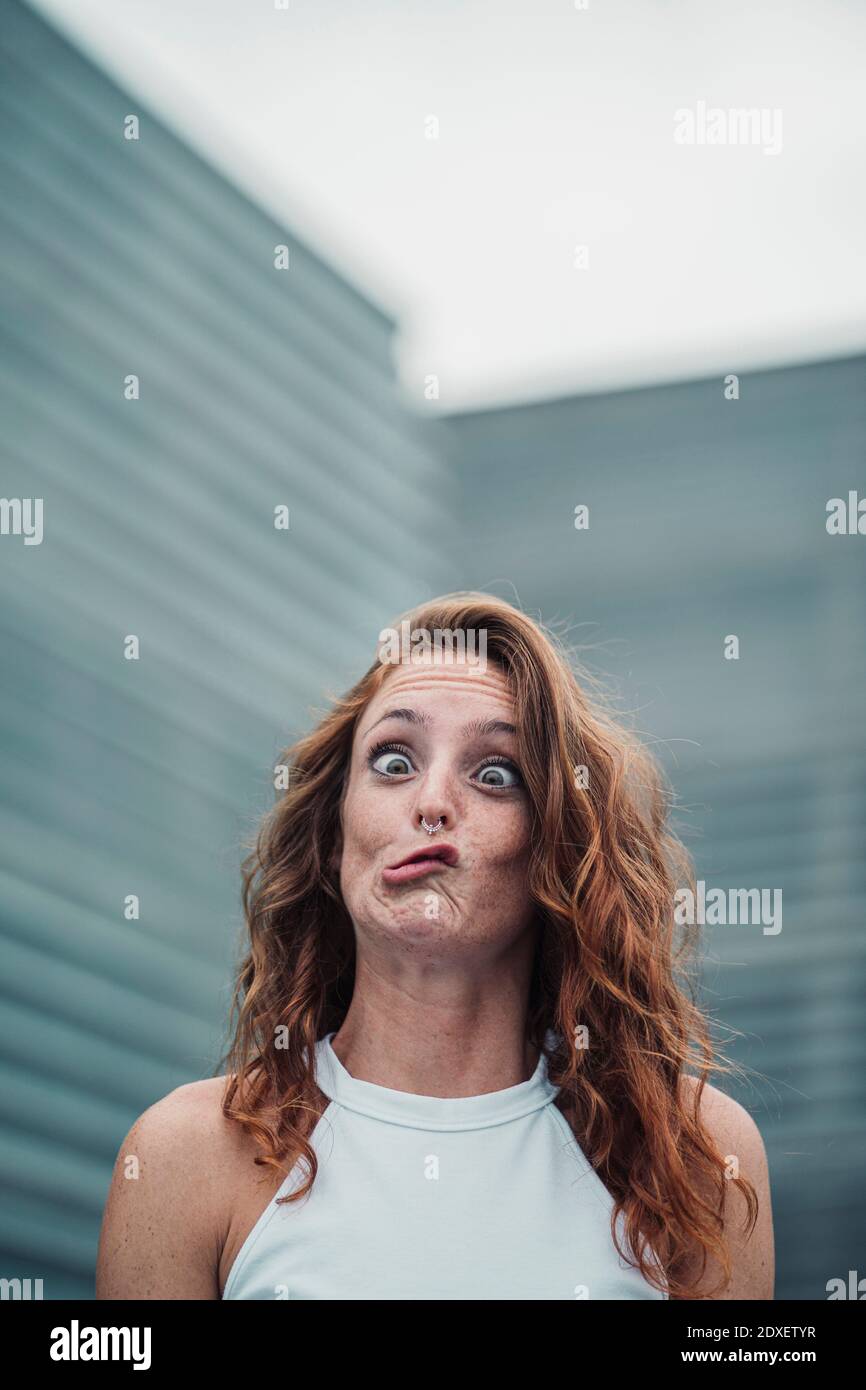 Young woman showing weird facial expression while standing outdoors Stock Photo