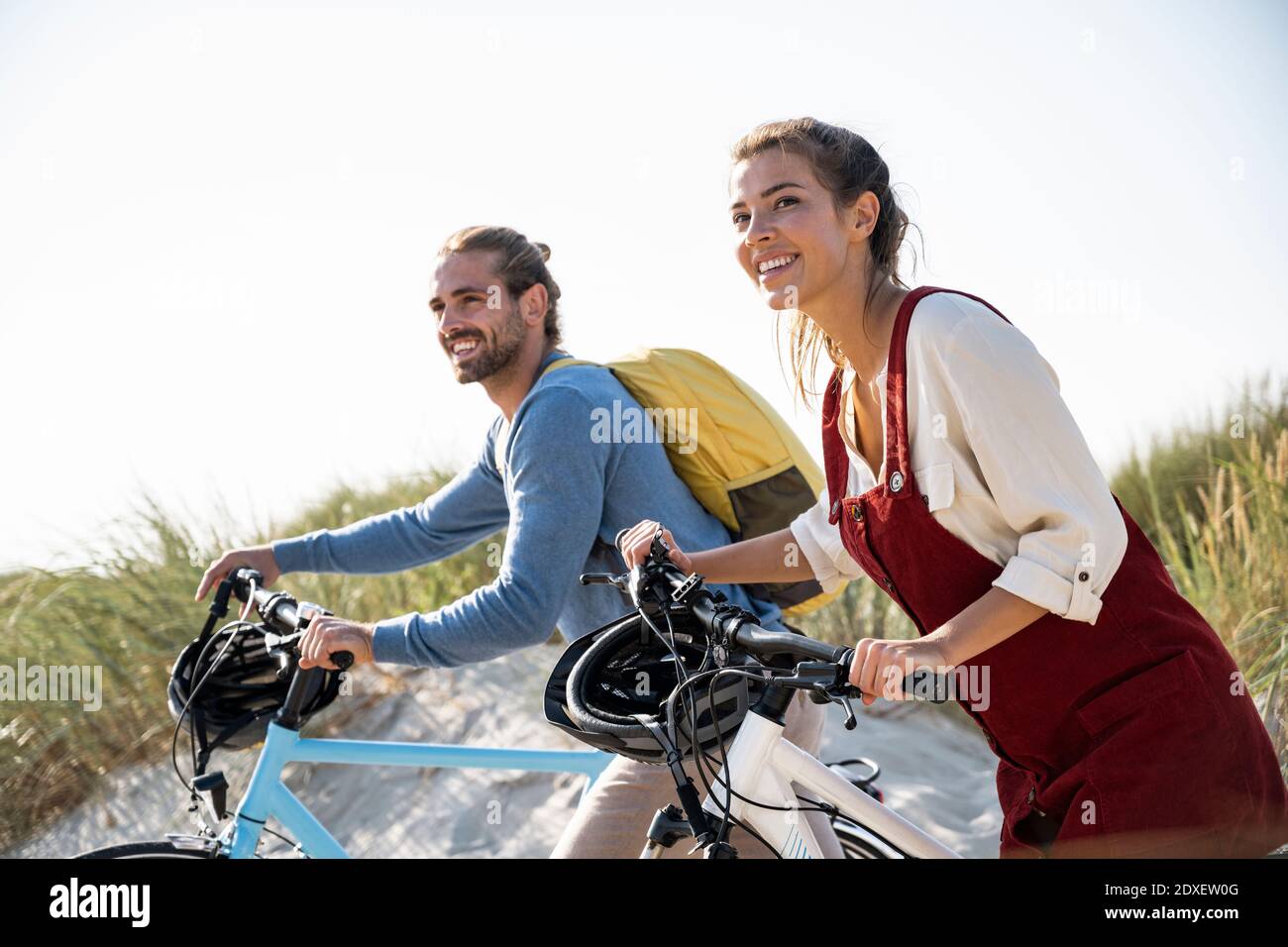 Couple with bicycles walking against clear sky Stock Photo