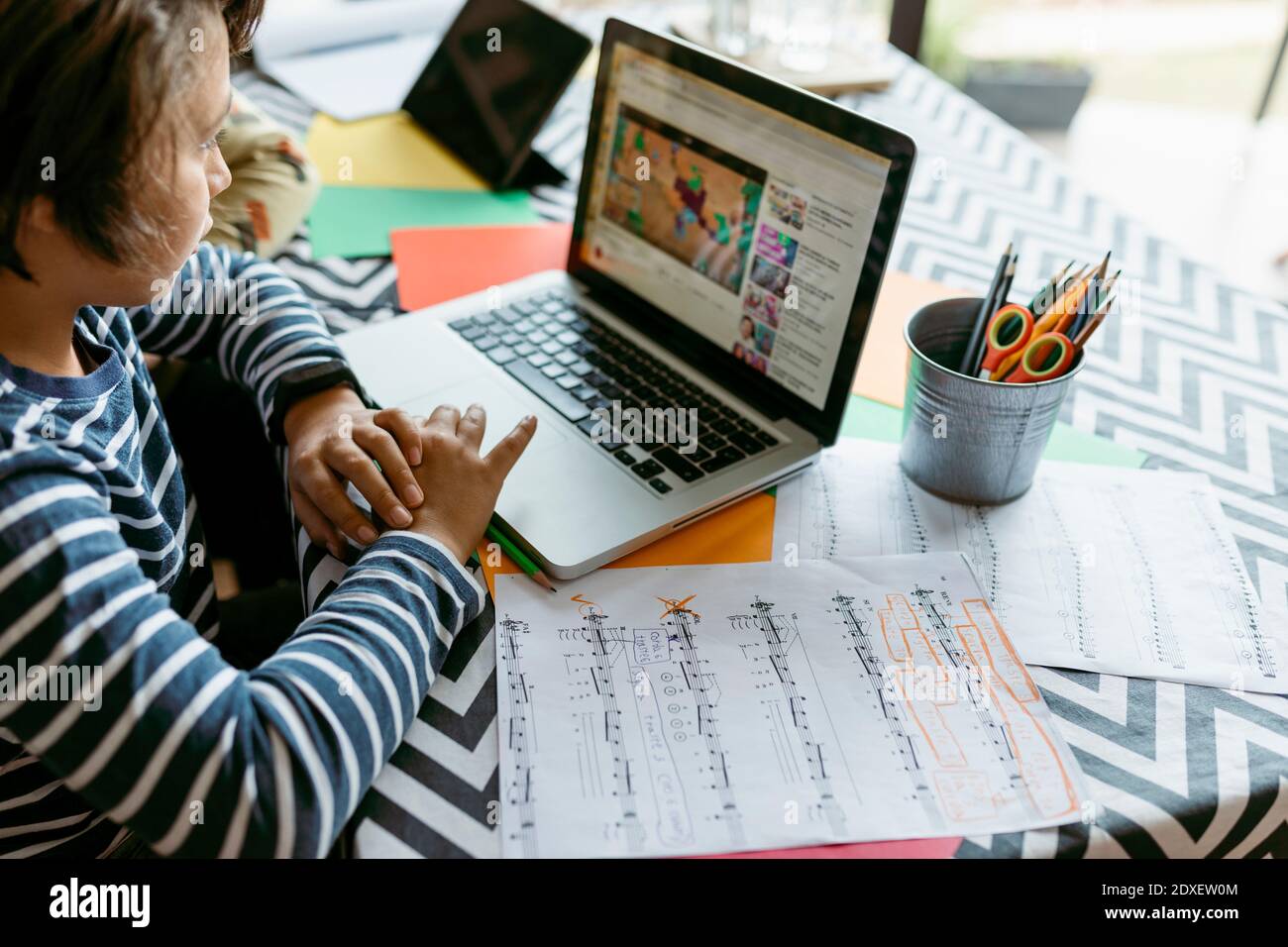 Boy watching online video on laptop while sitting at table Stock Photo