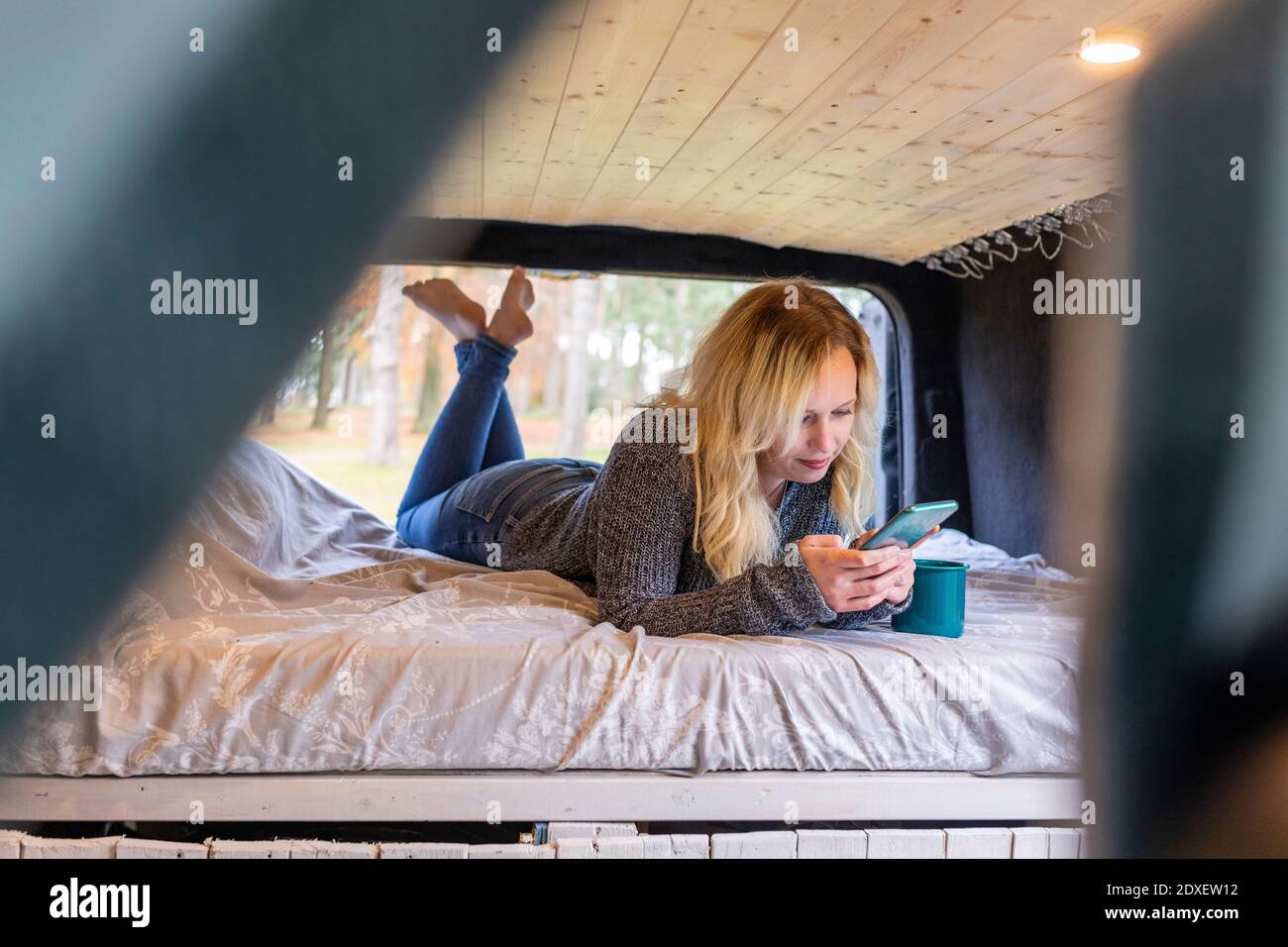 Mid adult woman using smart phone on bed in motor home Stock Photo