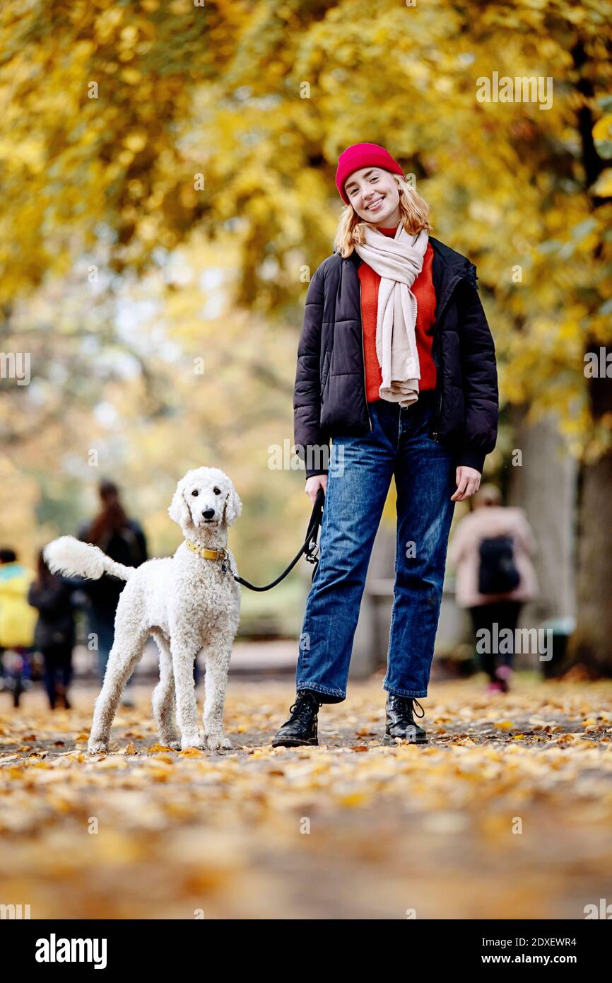 Smiling teenage girl with dog standing on road at park Stock Photo - Alamy
