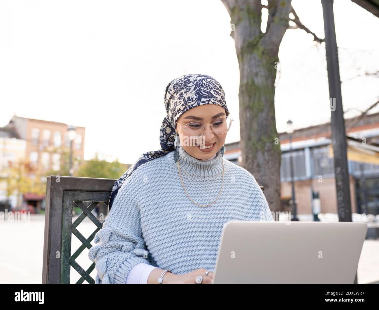 Smiling woman using laptop while sitting outdoors Stock Photo