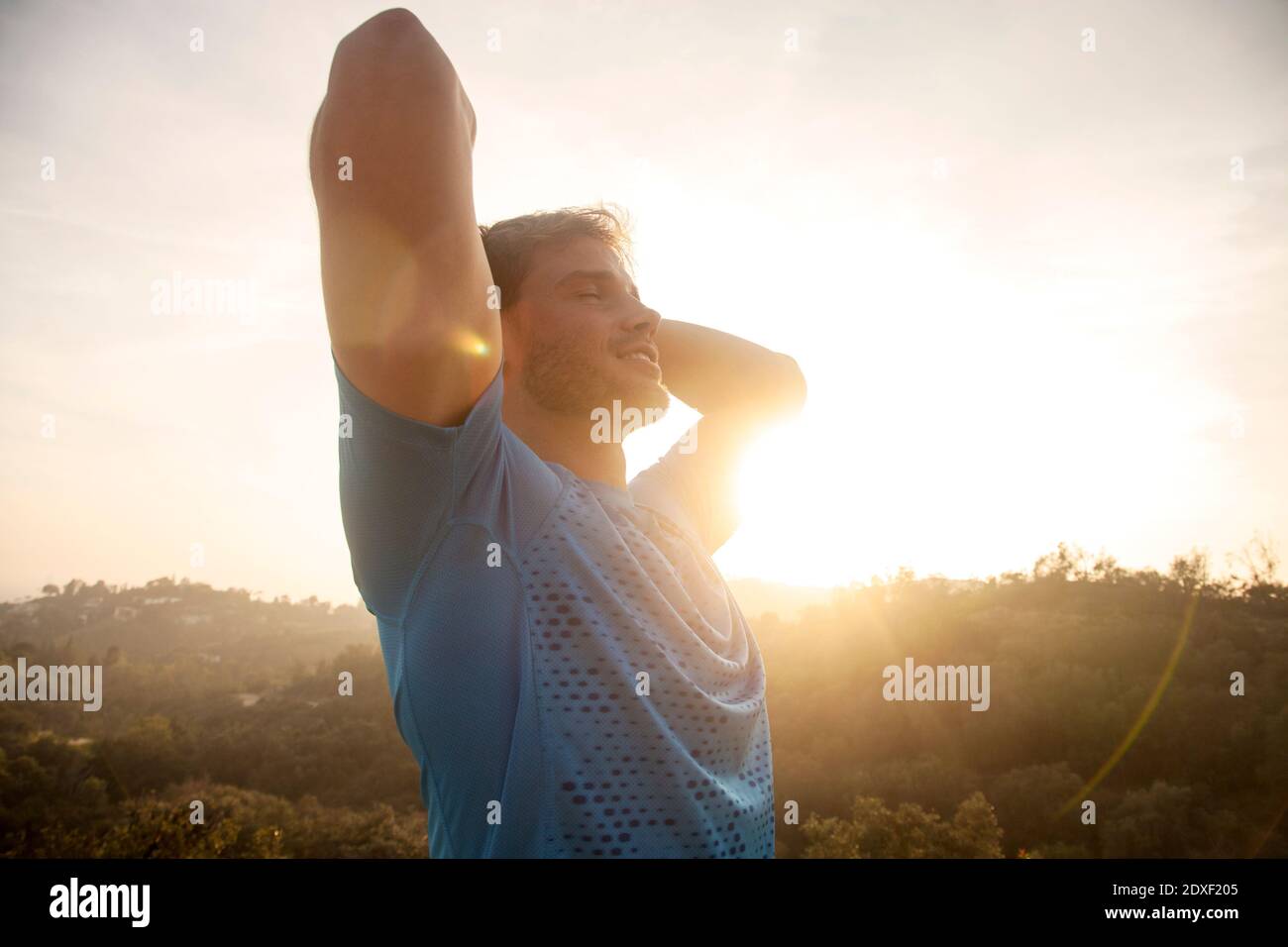 Man stretching arms while standing against sky Stock Photo